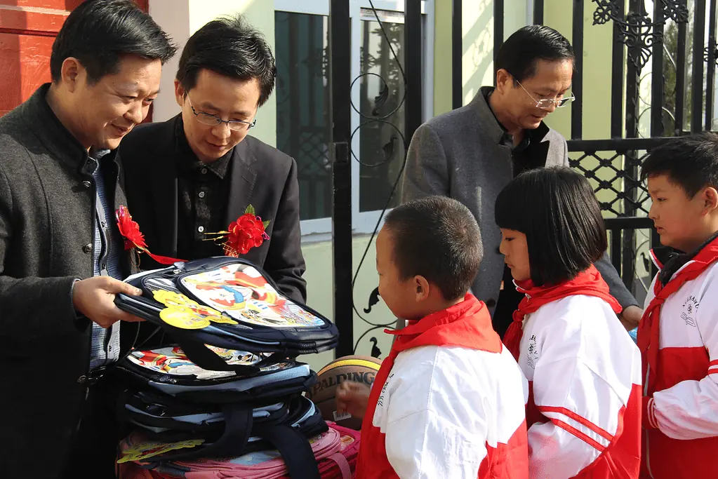 Kangli's founders distributing school bags to pupils during the Hope Primary School launching event.